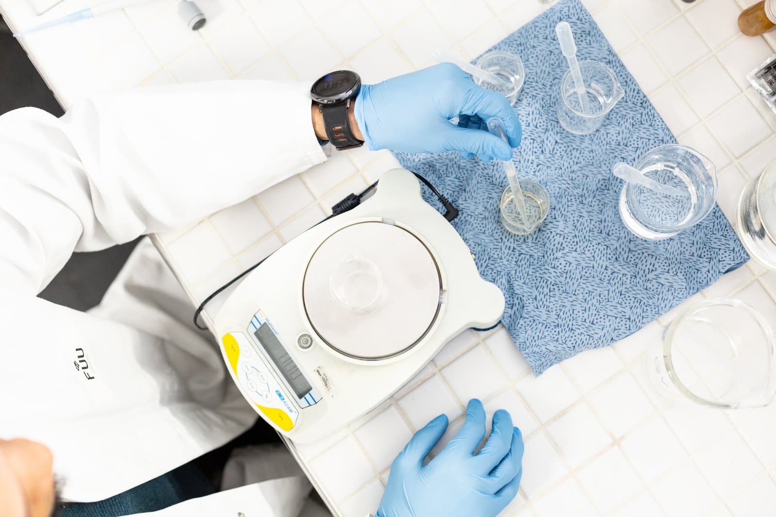 Dosage à la pipette dans un bécher posé sur une balance, au laboratoire Fuu.